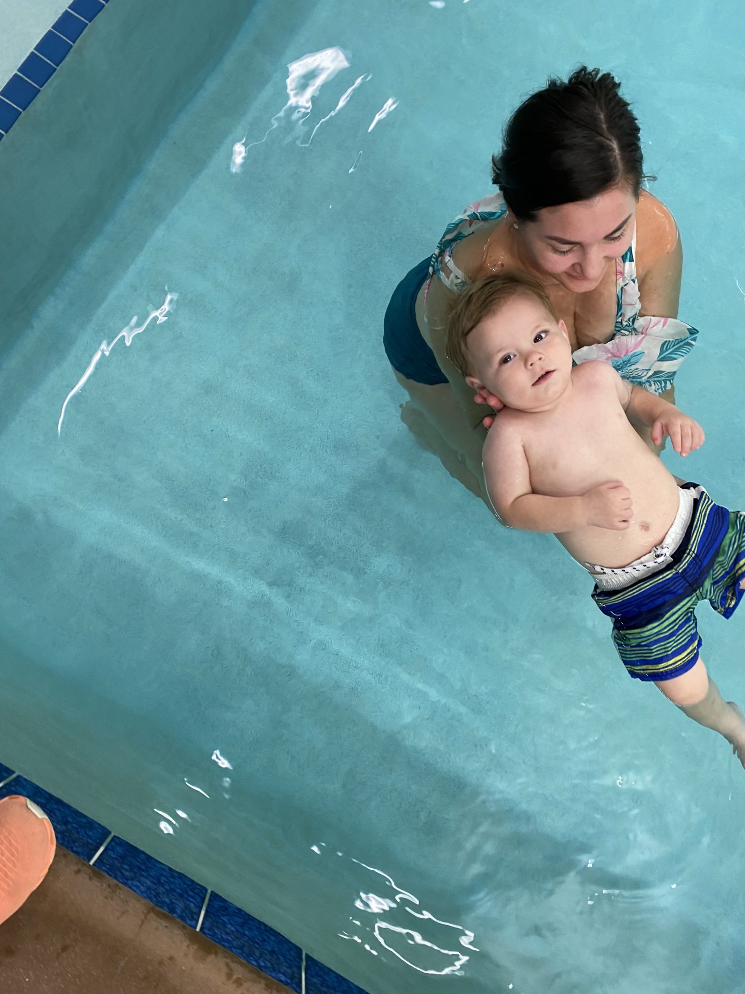 a mom holding her toddler as he floats on his back at Foss Swim School