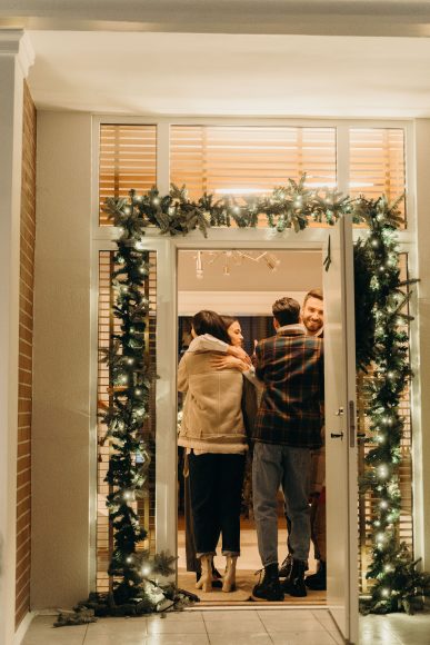 a couple greeting holiday guests at the door with a hug