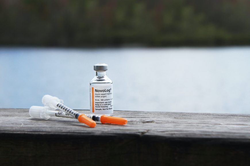 insulin and needles on a fence ledge by a lake