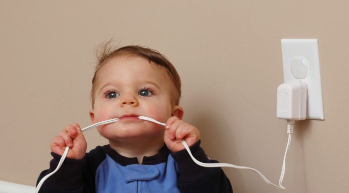 a baby chewing on a cord plugged into a wall