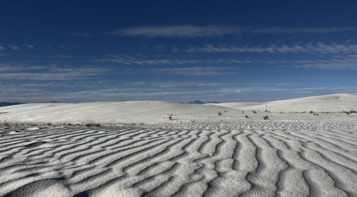 wavy lines in white sand in the foreground with a blue sky in the background