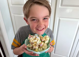 a young boy holding bowl full of popcorn with a big smile on his face