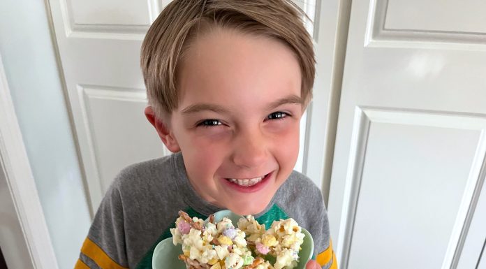 a young boy holding bowl full of popcorn with a big smile on his face