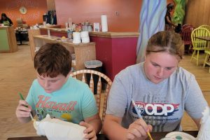 a boy and a girl painting pottery
