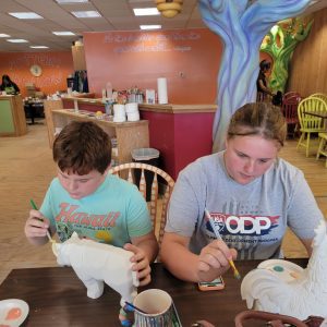 a boy and a girl painting pottery