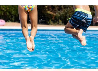 two kids from behind jumping into a pool