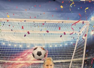 a young girl in a soccer net as a ball blazes over her head at an exhibit at the Missouri History Museum