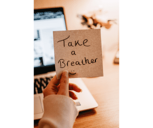 a woman holding a post-it note that says, “take a breather” so she doesn’t succumb to mom burnout