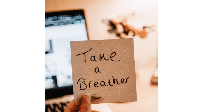 a woman holding a post-it note that says, “take a breather”