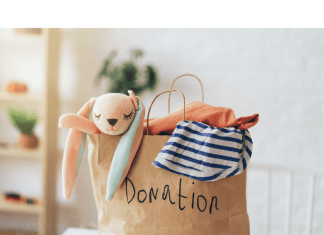 a paper bag with the word, “donations” written on it as clothing and stuffed animals spill out the top