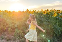 a boy and a girl walking through a field of sunflowers