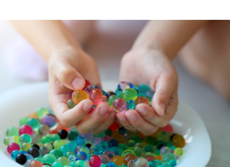 a child scooping up water beads from a bowl