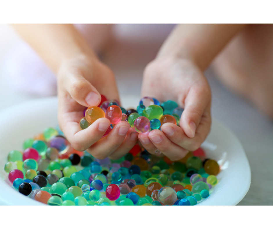 a child scooping up water beads from a bowl