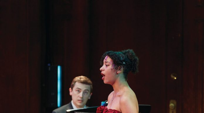 a singer in a red dress accompanied by a man on the piano at Opera Theatre of St. Louis