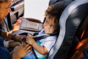 a mom buckling her baby in to a car seat