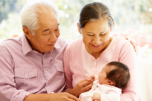 An Asian grandpa and grandma holding their grand baby