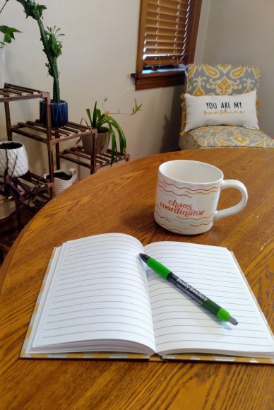 an lined notebook with a pen sitting open on a table next to a coffee mug