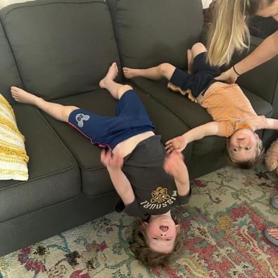 two young kids hanging upside down off of the couch