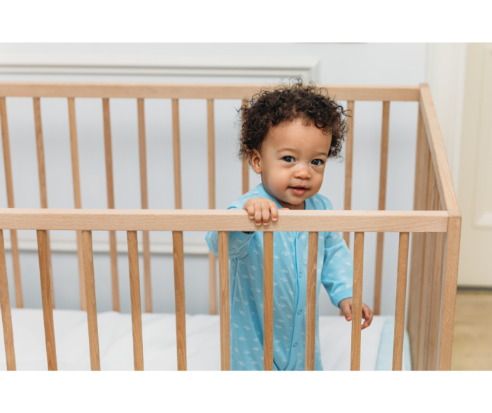 a baby standing up in a crib 