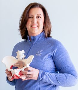 Brook Kalisiak, owner of Legacy Physical Therapy in St. Louis, holding a model of a pelvis