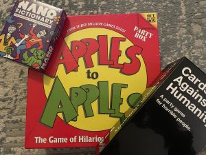 Apples to Apples, Nano Dictionary and Cards Against Humanity displayed on the carpet.