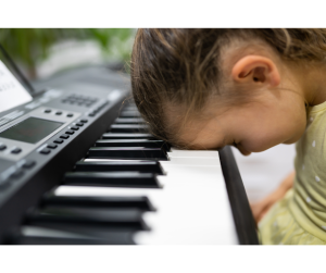 a girl with her head on the keys of an electric keyboard