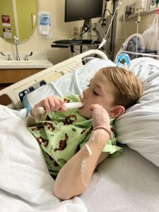 a boy eating a popsicle in a hospital bed after having a Tonsillectomy