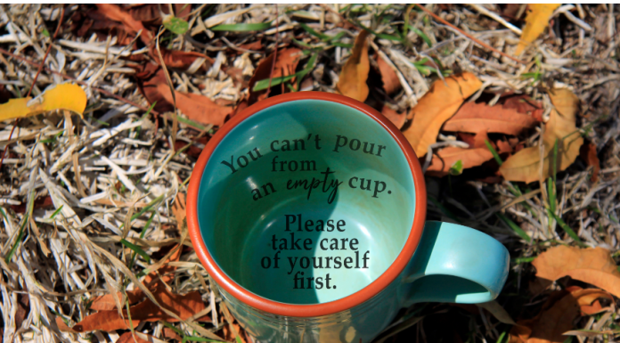 a coffee mug in the grass with the words, "you can't pour from an empty cup. Take care of yourself first."