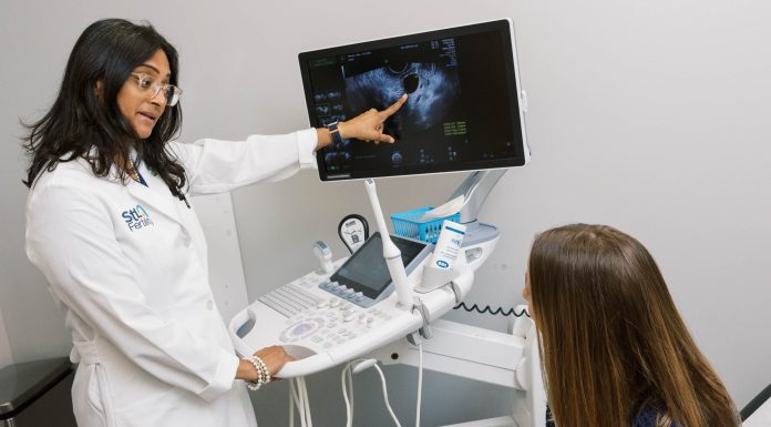 a doctor in front of an ultrasound machine, talking to a patient about what they see on the image