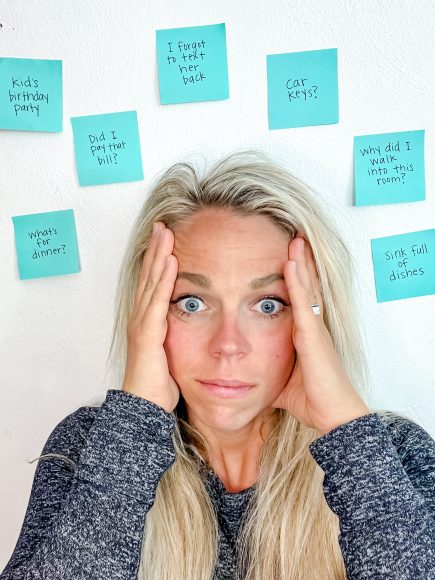 a mom with her eyes wide, hands up on the side of her face as she is surrounded by post it notes symbolizing ADHD as a mom