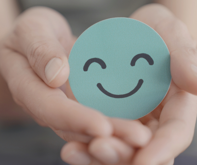 a close up of a child's hands holding a smiley face as a symbol of child or teen mental health and wellness