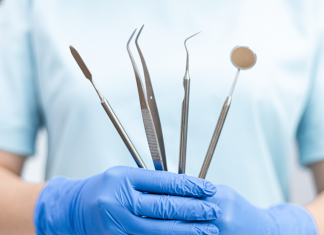 a close up of a dentist holding tools, wearing rubber gloves