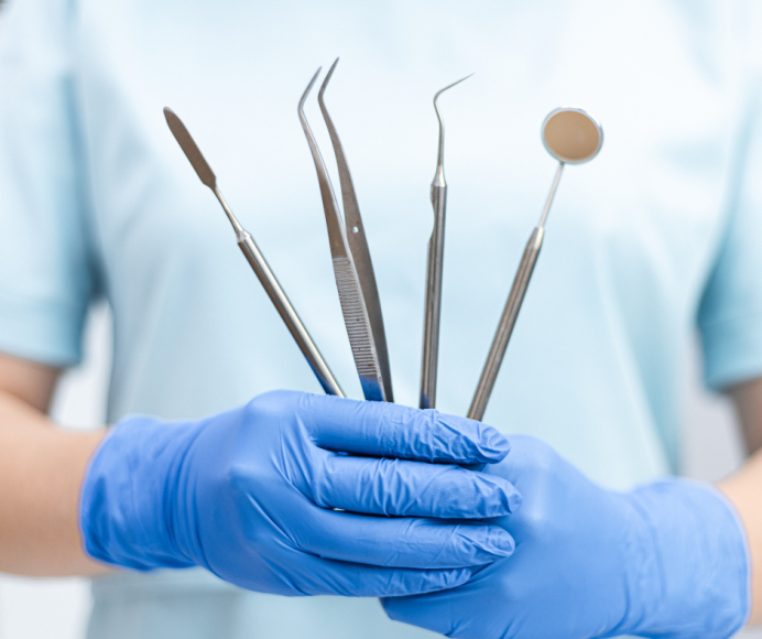 a close up of a dentist holding tools, wearing rubber gloves