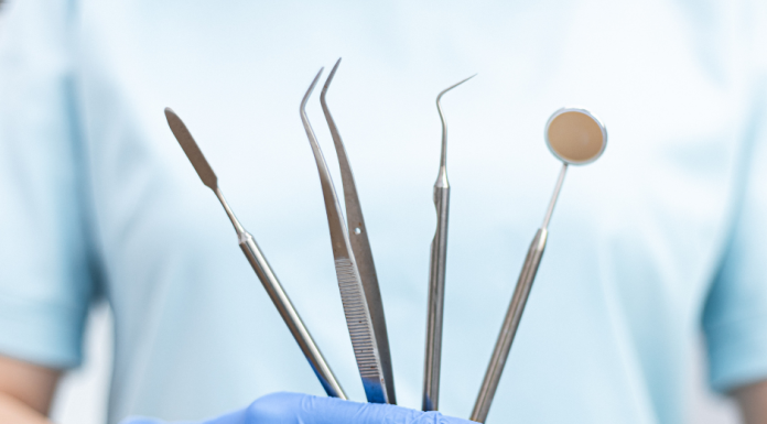 a close up of a dentist holding tools, wearing rubber gloves