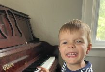 a young boy smiling as he plays the piano during music lessons