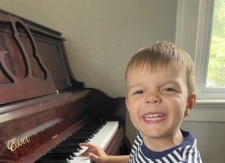 a young boy smiling as he plays the piano during music lessons