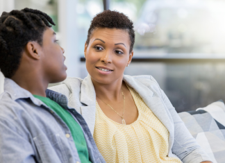 a mom sitting on the couch, talking to her teenaged son, checking in on the mental health needs of her children