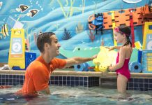 a male swim instructor encouraging a young girl to swim at Goldfish Swim School