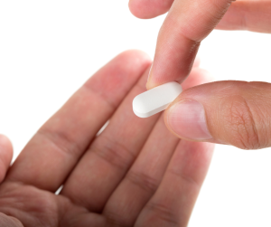 a close up of someone holding ADHD medication in one hand, putting it into another open hand