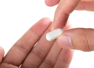 a close up of someone holding ADHD medications in one hand, putting it into another open hand