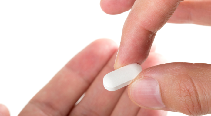 a close up of someone holding ADHD medications in one hand, putting it into another open hand