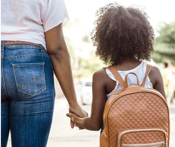 the view from behind of a mom walking her daughter to kindergarten