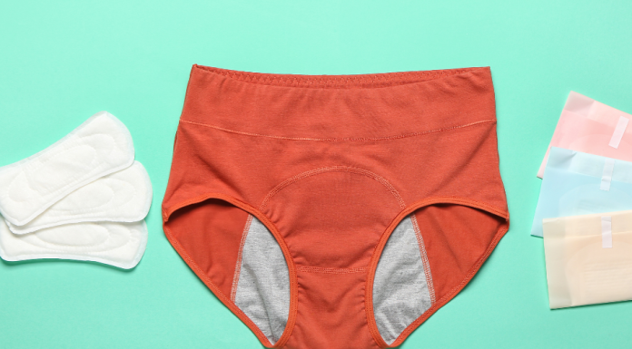 a pair of period underwear on a sea green background with tampons and pads next to it