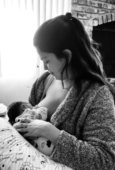 a black and white photo of a mom breastfeeding her baby