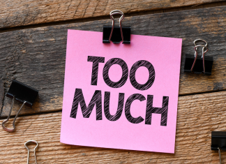 a pink post it note with the words, "too much" on a wooden background