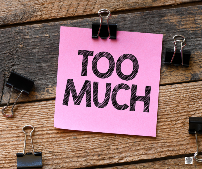 a pink post it note with the words, "too much" on a wooden background