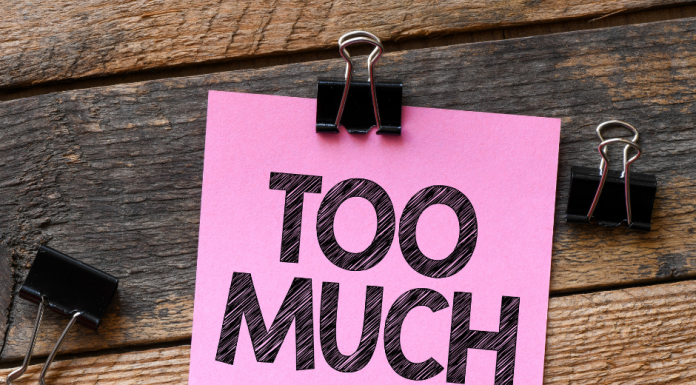 a pink post it note with the words, "too much" on a wooden background