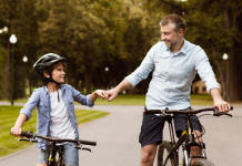 a father and son, side-by-side on bikes as they fist bump each other