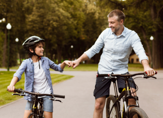 a father and son, side-by-side on bikes as they fist bump each other