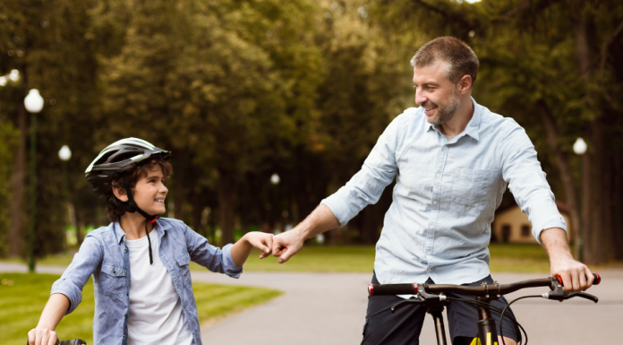 a father and son, side-by-side on bikes as they fist bump each other